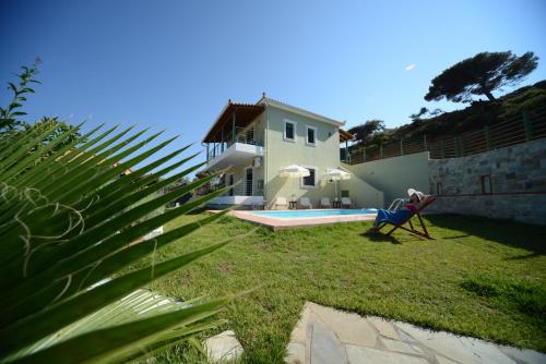 a house with a yard with a chair and a pool at Aselinos Suites in Koukounaries
