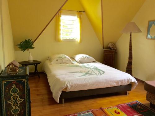 a bedroom with a bed with a yellow ceiling and a window at villa MILA in Ravine Sèche