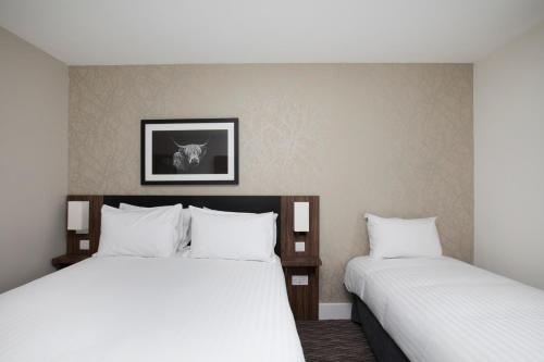 two beds in a hotel room with white sheets at Spring River Ebbsfleet by Marston's Inns in Gravesend