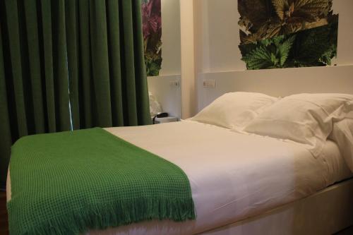 a white bed with a green blanket on it at Hotel Lino in Vigo