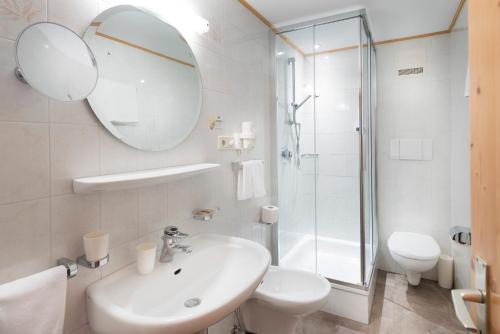 a bathroom with a sink and a toilet and a mirror at Hotel Zum Turm in Castelrotto