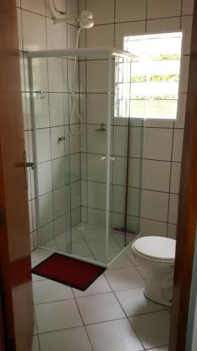 ウバトゥバにあるSuítes Ubatuba Praia da Lagoinhaのガラス張りのシャワーとトイレ付きのバスルーム
