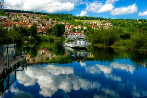 a boat is docked in a river with a town at Evasion Tonique in Villers-le-Lac