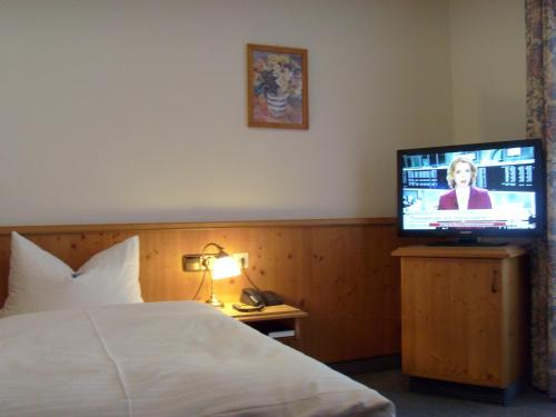 a hotel room with a bed and a flat screen tv at Landhotel & Gaststuben Zum Hasen in Bad Saulgau