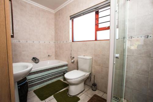 uma casa de banho com um WC, uma banheira e um lavatório. em Spacious Garden Cottage em Joanesburgo