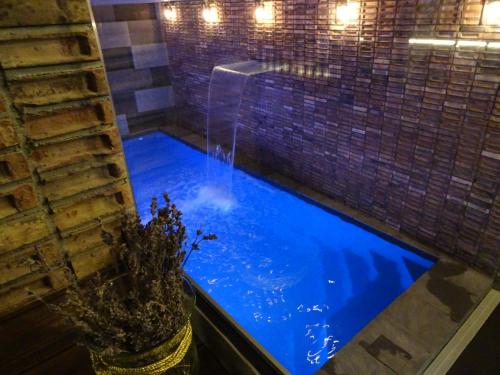 a large blue pool with a waterfall in a bathroom at Penzion Zlaty Orol in Helcmanovce