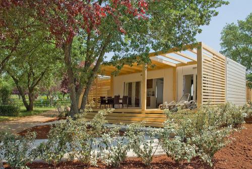 una pequeña casa con una gran terraza en un patio en Holiday Mobile Homes Park Riviera en Novigrad Istria