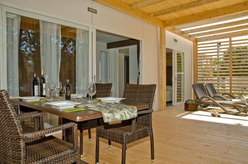 a dining room table with chairs and wine glasses at Holiday Mobile Homes Park Riviera in Novigrad Istria