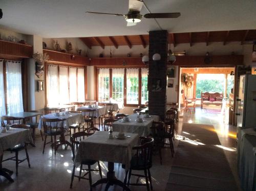 a dining room with tables and chairs and windows at Alpina Hostería in Villa Gesell