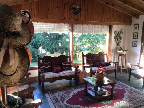 una sala de estar con sillas y una mesa en la Alpina Hostería de Villa Gesell