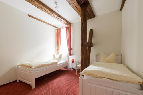 a bedroom with two white beds and a window at Ferienwohnungen am Klint in Wernigerode