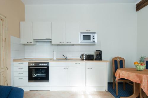 a kitchen with white cabinets and a microwave and a table at Ferienwohnungen am Klint in Wernigerode