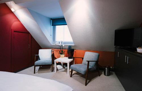 ブルージュにあるAround the cornerの椅子2脚、ベッド1台、テレビが備わる客室です。