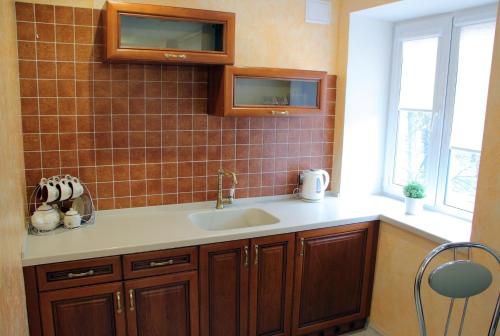 a kitchen with a sink and a tile wall at Apartment on Prospekt Mira in Chernihiv