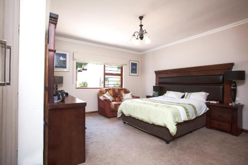 ein Schlafzimmer mit einem Bett und einem Stuhl und einem Fenster in der Unterkunft Spacious Garden Cottage in Johannesburg
