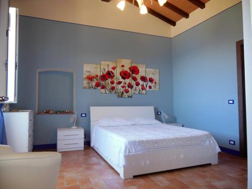 a bedroom with a white bed with red flowers on the wall at La Casa Di Ninetta in Rio Marina