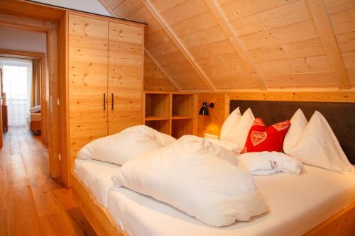 a bedroom with a bed with white sheets and red pillows at Trattlers Hof-Chalets in Bad Kleinkirchheim