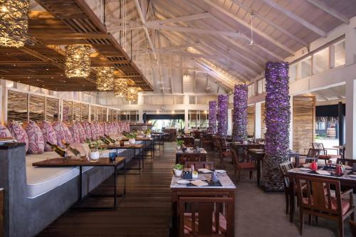 un restaurant avec des tables, des chaises et des piliers violets dans l'établissement Taj Coral Reef Resort & Spa,Maldives - Premium All Inclusive with Free Transfers, à Atoll Malé Nord