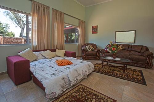 um quarto com uma cama, um sofá e uma mesa em Chalet no.1 Primula em Joanesburgo