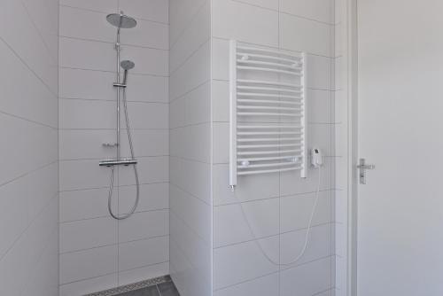 a white bathroom with a shower with a window at d'Ouwe Haven 10F in Kamperland