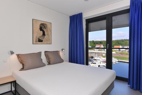 a bedroom with a bed with blue curtains and a window at d'Ouwe Haven 10F in Kamperland