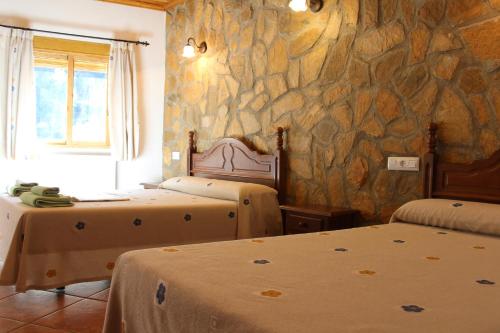 a bedroom with two beds and a stone wall at Hotel Spa Venta Ticiano in Yeste