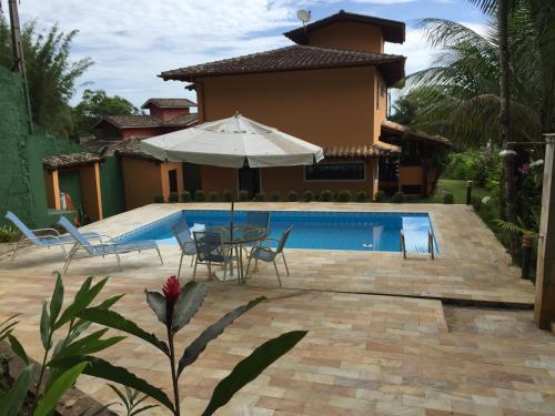een zwembad met stoelen en een parasol naast een huis bij Casa Praia de Santiago in São Sebastião