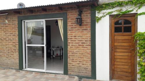 eine Glasschiebetür in einem Backsteingebäude mit einer Holztür in der Unterkunft Vero!! in General Rodríguez