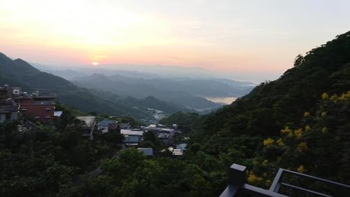 a view of a valley with the sun setting over mountains at Luck Homestay in Jiufen