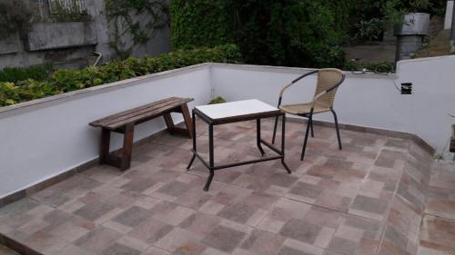 eine Bank, einen Tisch und einen Stuhl auf einer Terrasse in der Unterkunft Vero!! in General Rodríguez