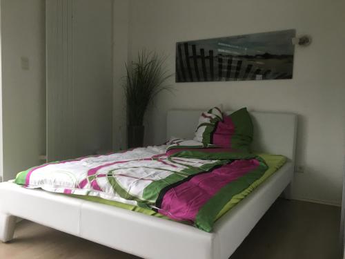 een wit bed met een kleurrijke deken erop bij Stadtvilla Intzeplatz - Apartment Juist in Remscheid