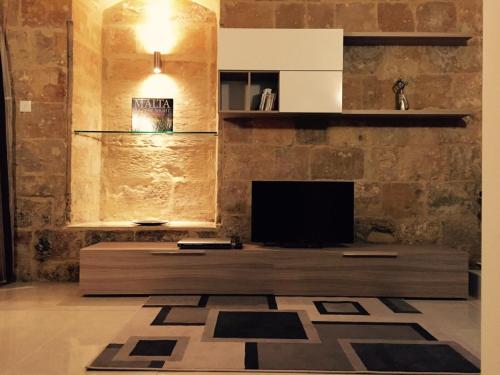 ein Wohnzimmer mit einem TV und einem Sofa in der Unterkunft Renovated 16th Century House in Valletta in Valletta