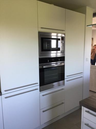 a kitchen with white cabinets and a microwave at Seaview in Pleubian