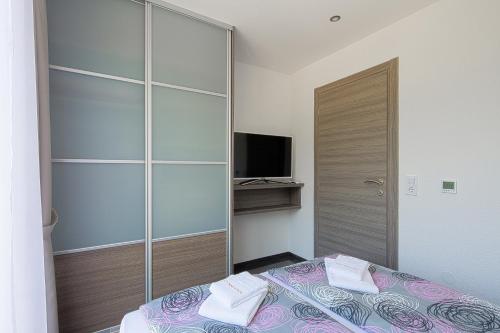 a bedroom with a bed and a closet with a television at Montelux Apartments in Budva