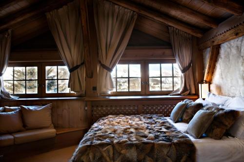 a bedroom with a large bed and windows at Chalet des Fermes de Marie, avec services, Collection Chalets des Fermes in Megève