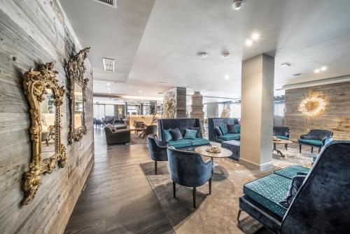 a lobby with blue chairs and a wall with a mirror at Hotel Spinale in Madonna di Campiglio