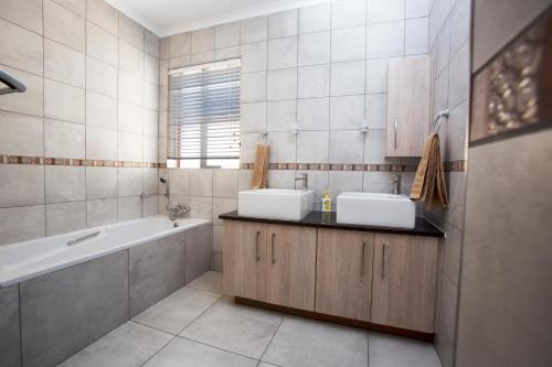 a bathroom with two sinks and a bath tub at Chalet no. 2 Petunia in Johannesburg