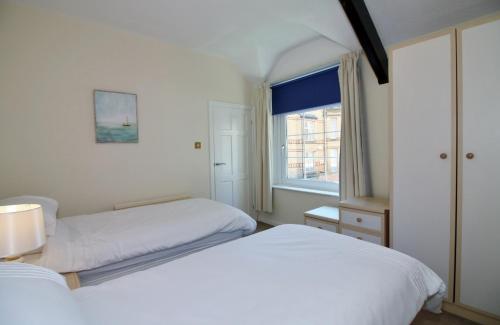 a white bedroom with two beds and a window at The Coach House Apartment in Lytham St Annes