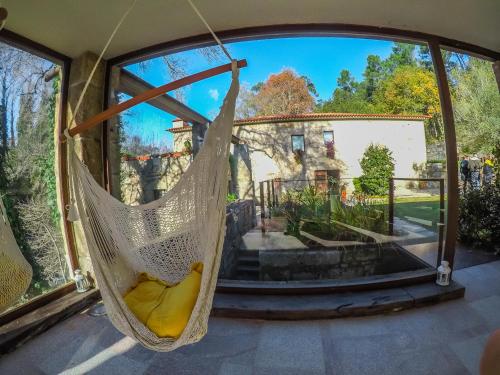 a hammock in a house with a view of a yard at Azenha do Trigo in Rendufe