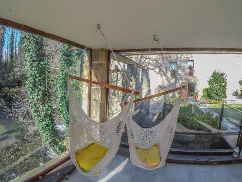 two hammocks hanging in front of a window at Azenha do Trigo in Rendufe