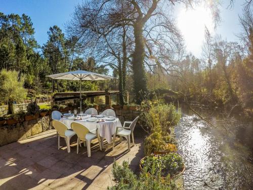 a table with chairs and an umbrella next to a river at Azenha do Trigo in Rendufe