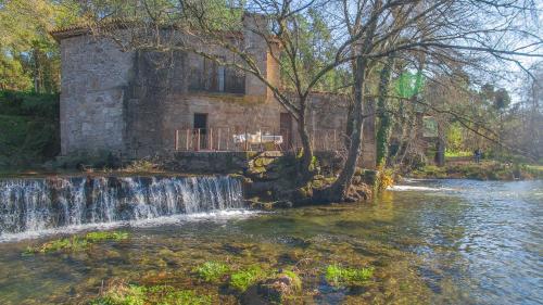 a waterfall in front of a building next to a river at Azenha do Trigo in Rendufe