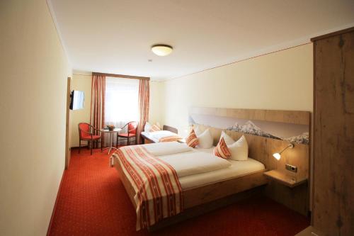 ビショフスヴィーゼンにあるAlpenhotel Brennerbaschtのベッド、テーブル、椅子が備わるホテルルームです。