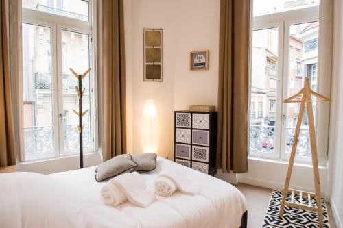 een slaapkamer met een wit bed en handdoeken bij Le Saint-Aubin by Cocoonr in Toulouse