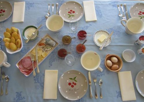 un tavolo con piatti e utensili e cibo sopra di La maison des fleurs a Saint-Senoch