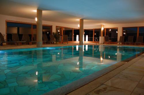 a large swimming pool in a hotel with chairs at Hotel Gstatsch in Alpe di Siusi