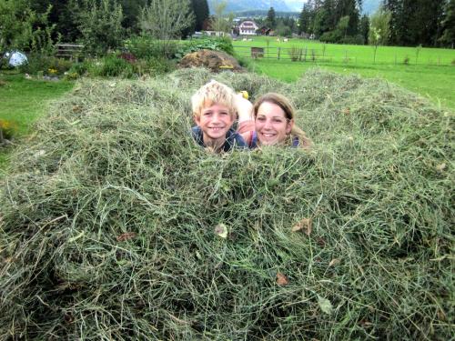 two children are laying in a pile of hay at Gästehaus Jäger in Mariapfarr