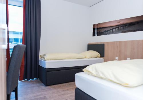a bedroom with two beds and a chair and a window at Hotel Staffelseestraße in Munich