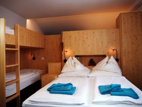 a bedroom with a bed with two blue towels on it at DAV-Haus (Alpenverein) in Obertauern