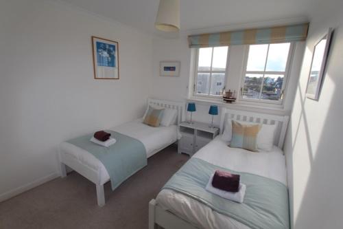 1 dormitorio con 2 camas y 2 ventanas en No 10 Royal Apartments, en North Berwick